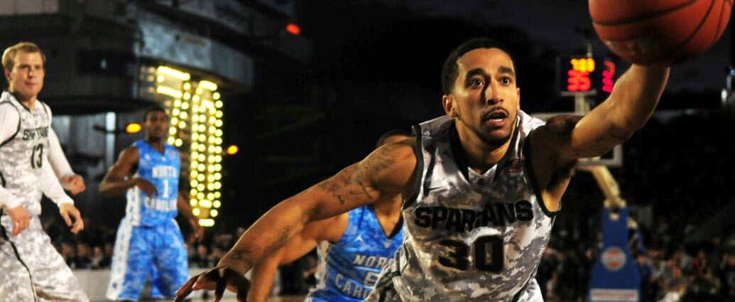 Intense basketball game with athletes in action on an outdoor court during nighttime.
