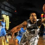 Intense basketball game with athletes in action on an outdoor court during nighttime.