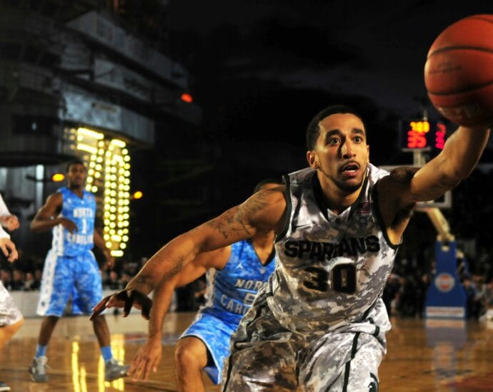 Intense basketball game with athletes in action on an outdoor court during nighttime.