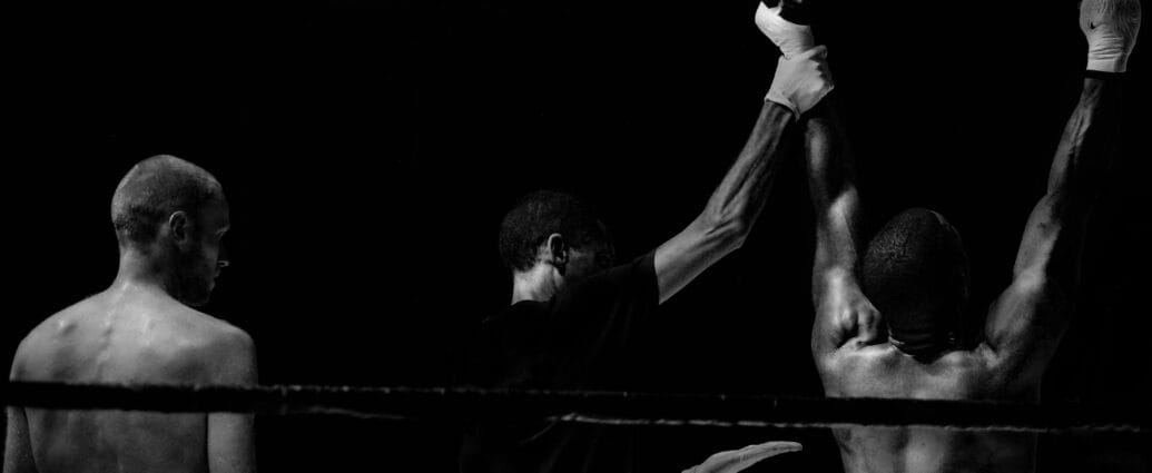 Black and white image capturing a victorious boxing moment in the ring.