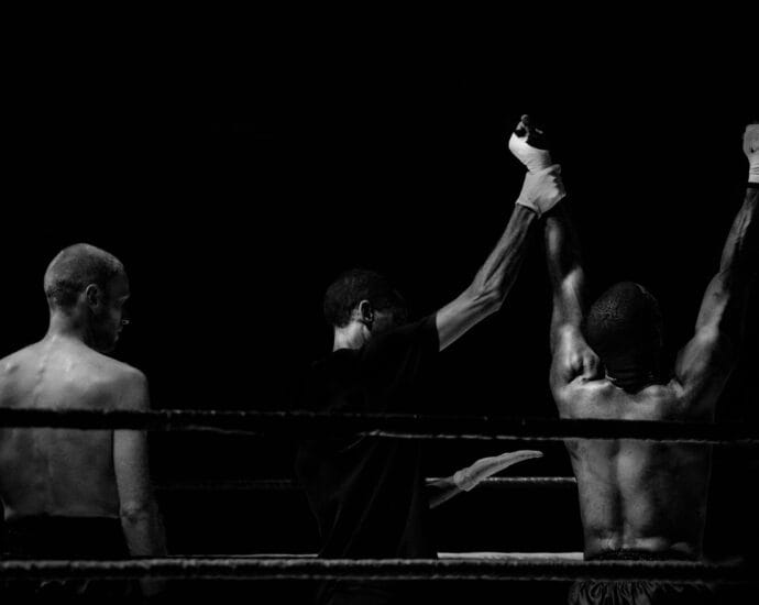 Black and white image capturing a victorious boxing moment in the ring.