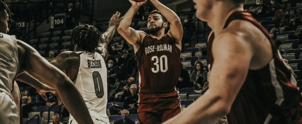Basketball players in an intense college game action, showcasing skill on court.
