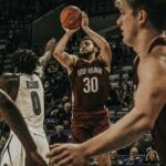 Basketball players in an intense college game action, showcasing skill on court.