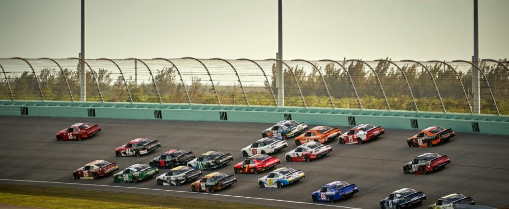 High-speed NASCAR race featuring multiple cars on a sunny day in Miami.