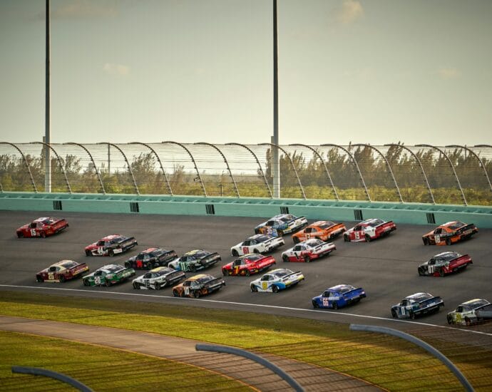 High-speed NASCAR race featuring multiple cars on a sunny day in Miami.