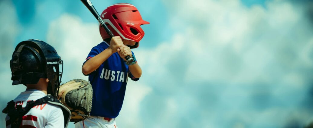 Young baseball players during a game, featuring a batter and a catcher in protective gear.