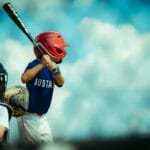 Young baseball players during a game, featuring a batter and a catcher in protective gear.