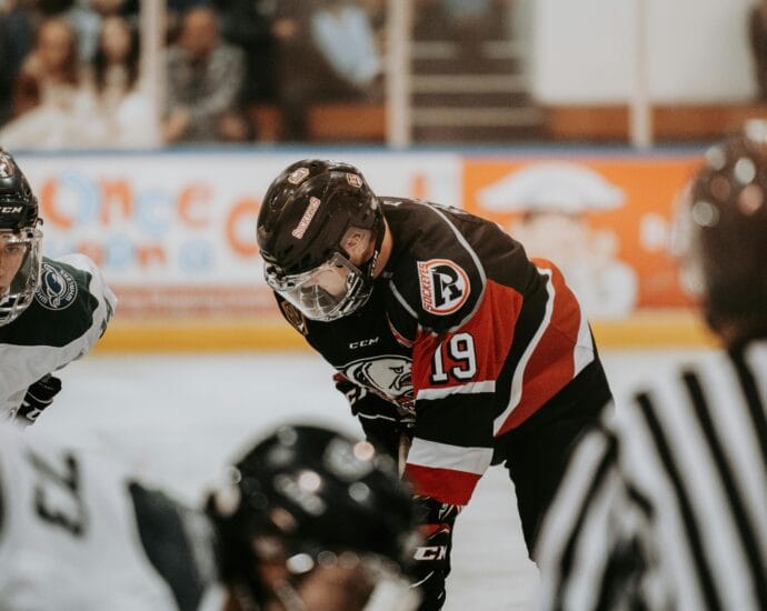 Close-up action scene of ice hockey players in full gear competing on an indoor rink.