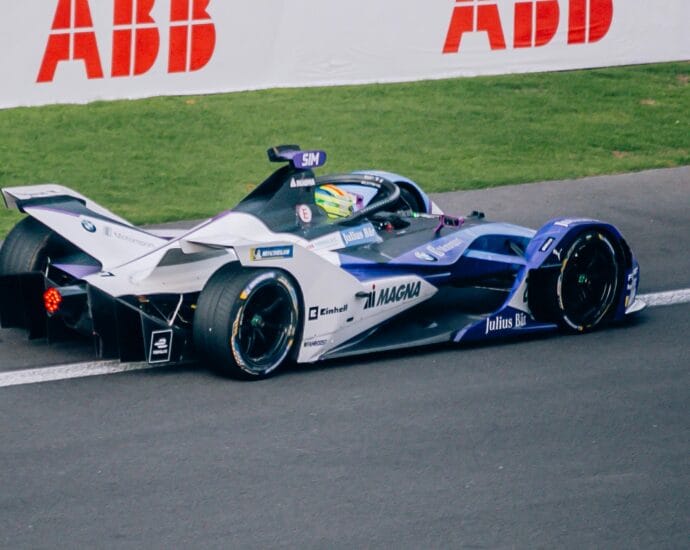 A Formula E race car speeds on track at a racing event in Mexico City, showcasing high-tech engineering.