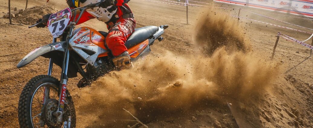 Dynamic motocross scene with rider kicking up dust on a dirt track.