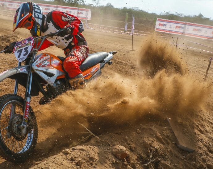Dynamic motocross scene with rider kicking up dust on a dirt track.