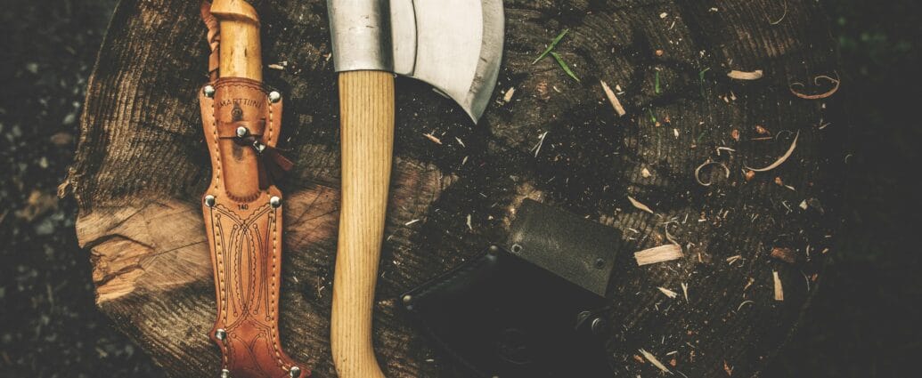 A rugged camping axe and knife on a tree stump, perfect for bushcraft and outdoor adventures.