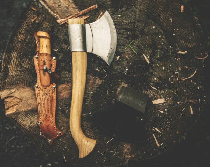 A rugged camping axe and knife on a tree stump, perfect for bushcraft and outdoor adventures.