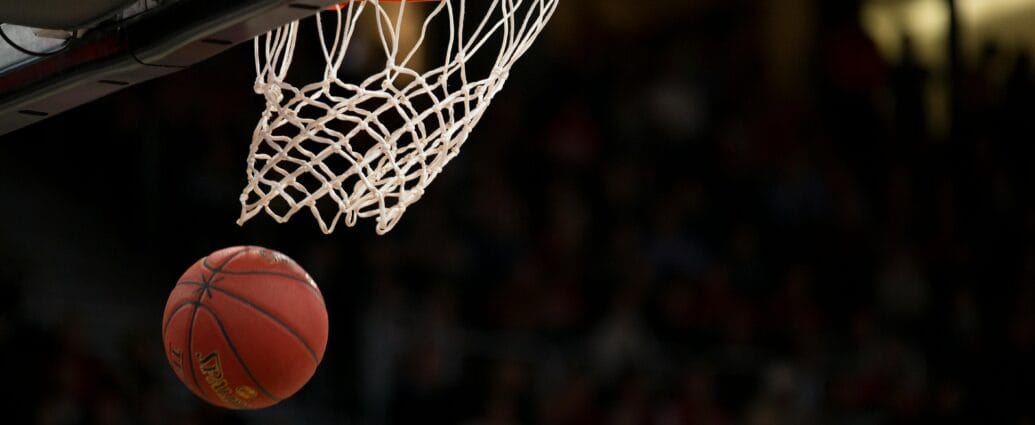 A basketball going through the hoop during a fast-paced game, capturing the excitement of the sport.