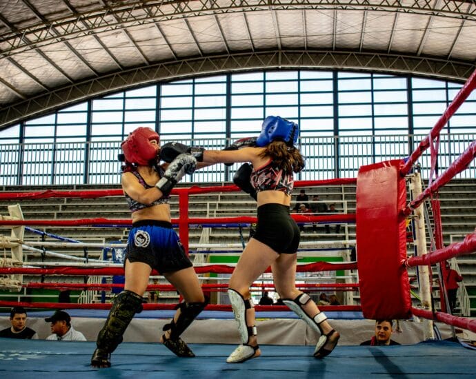 Dynamic kickboxing match between two women in a stadium ring.