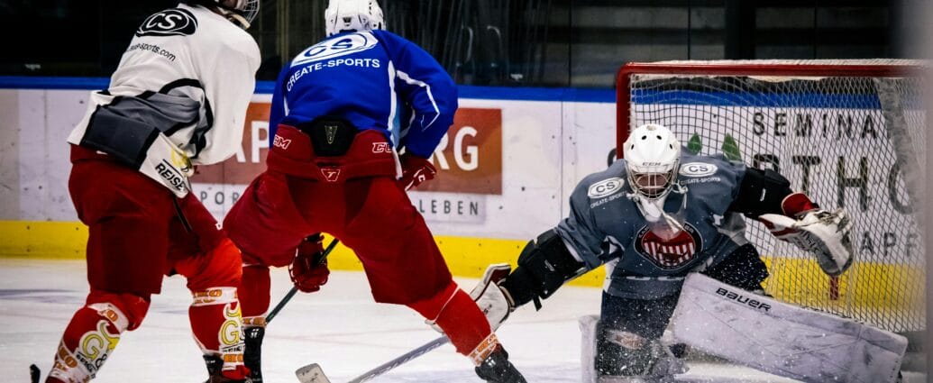 Dramatic moment in an indoor ice hockey game with players in action against a goalie.