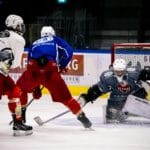 Dramatic moment in an indoor ice hockey game with players in action against a goalie.