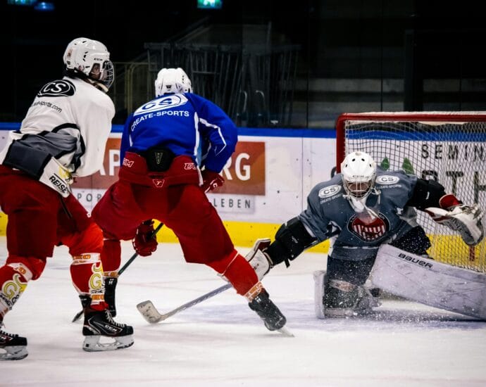 Dramatic moment in an indoor ice hockey game with players in action against a goalie.