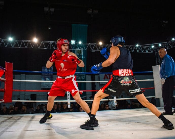 Two amateur boxers in a heated match inside a professional boxing ring.