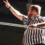 Referee signaling during an intense wrestling match, indoors.