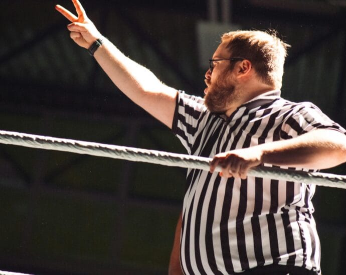 Referee signaling during an intense wrestling match, indoors.