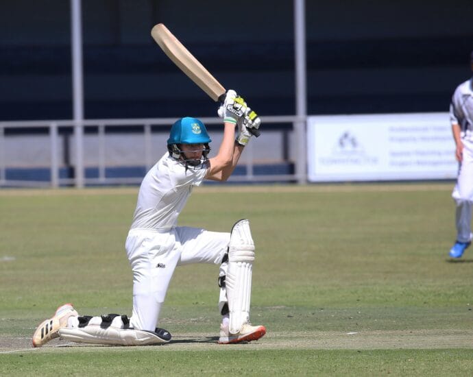 Two young cricketers playing a match, showcasing batting skills on the field.