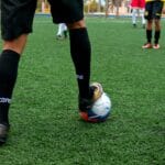 Close-up of a soccer player controlling the ball during a match on a green field.