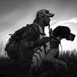 Hunter in camouflage with his dog at sunrise in Florida fields.