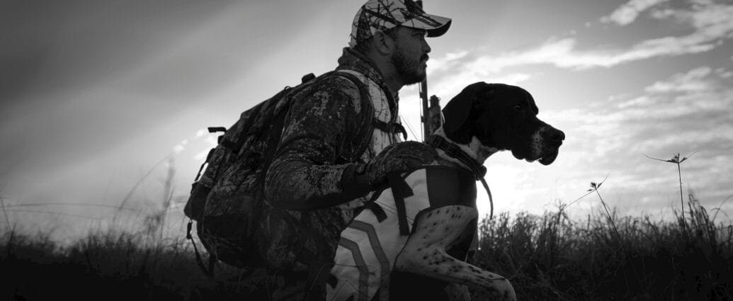 Hunter in camouflage with his dog at sunrise in Florida fields.