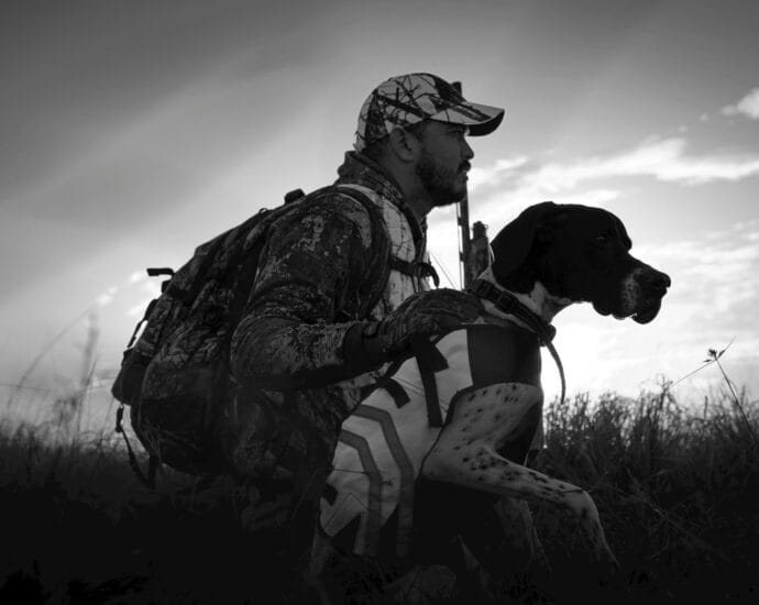 Hunter in camouflage with his dog at sunrise in Florida fields.