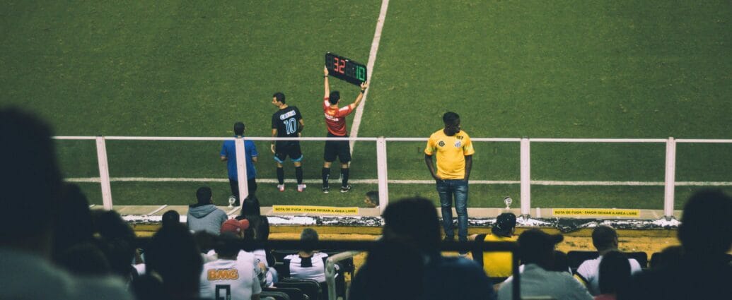 Soccer player substitution during a match at a stadium with an engaged audience.