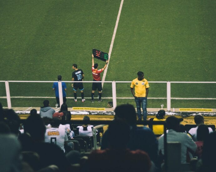 Soccer player substitution during a match at a stadium with an engaged audience.