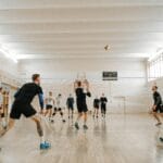 Indoor volleyball match featuring mixed-gender teams actively playing and competing.