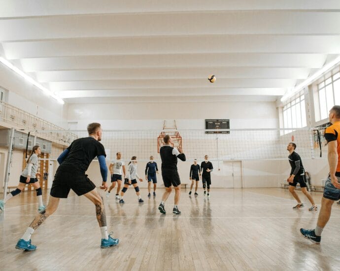 Indoor volleyball match featuring mixed-gender teams actively playing and competing.
