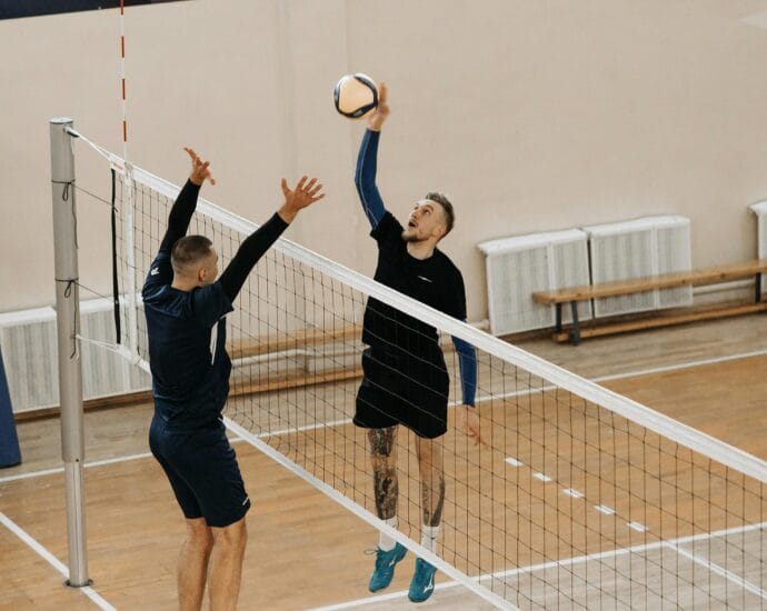 Two male athletes playing a competitive volleyball game indoors.