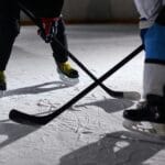 Close-up of hockey players battling for puck during an intense face-off on a lighted ice rink.