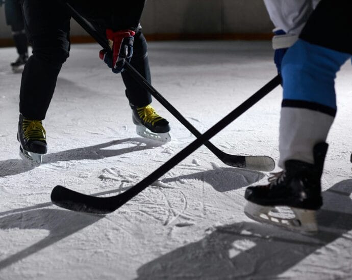 Close-up of hockey players battling for puck during an intense face-off on a lighted ice rink.