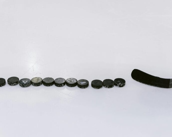 A row of hockey pucks and a stick on an ice rink, perfect for sports content.