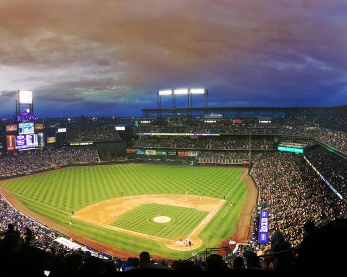 Wide-angle view of a baseball stadium at dusk capturing the field and excited crowd.