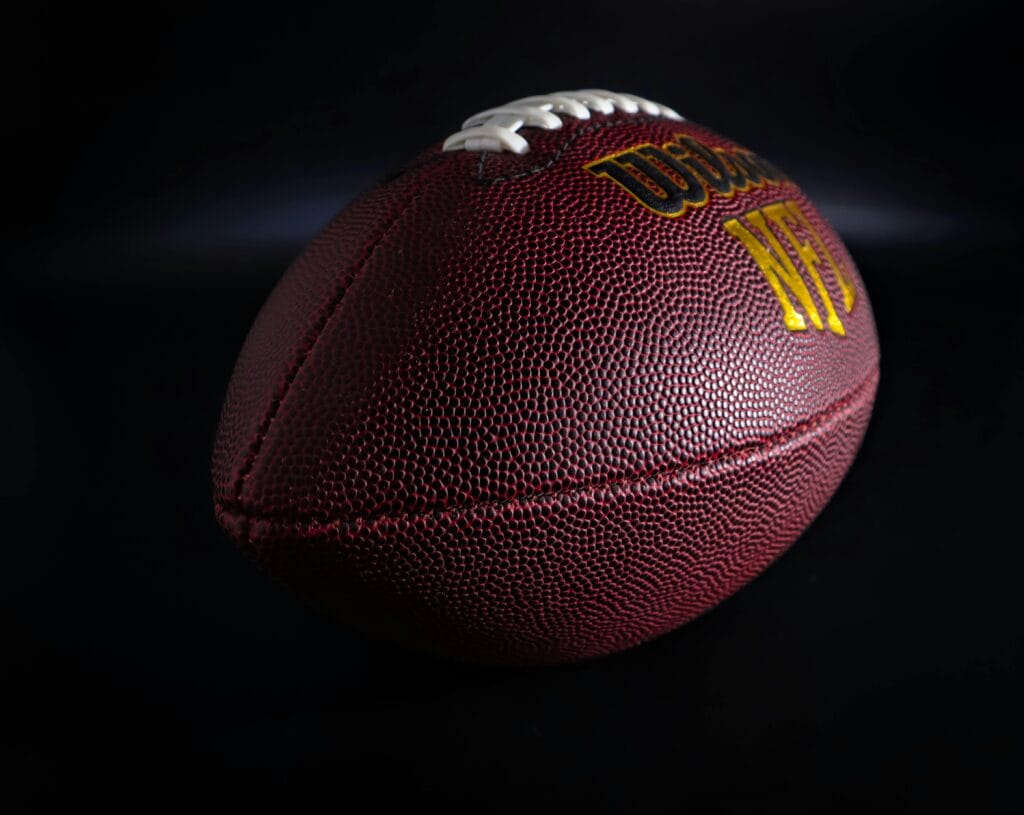 pexels-photo-10322267-10322267 Detailed view of a traditional brown and white American football against a dark backdrop, highlighting texture.