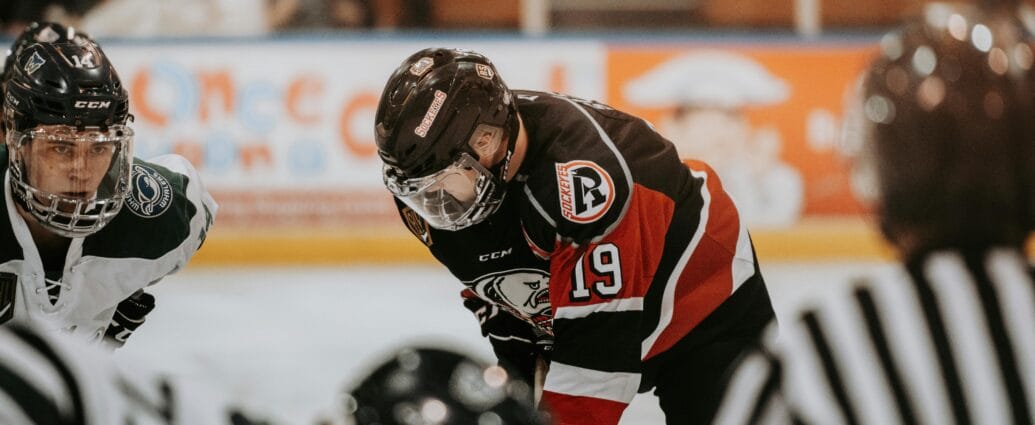 Close-up action scene of ice hockey players in full gear competing on an indoor rink.