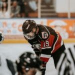 Close-up action scene of ice hockey players in full gear competing on an indoor rink.