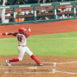 A baseball player powerfully swings the bat during a game, capturing the essence of competitive sports.