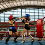 Dynamic kickboxing match between two women in a stadium ring.