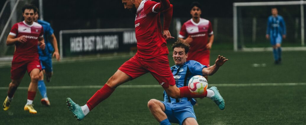 Intense soccer match with players in mid-jump and tackle on a green field. Captivating sports action.