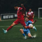 Intense soccer match with players in mid-jump and tackle on a green field. Captivating sports action.