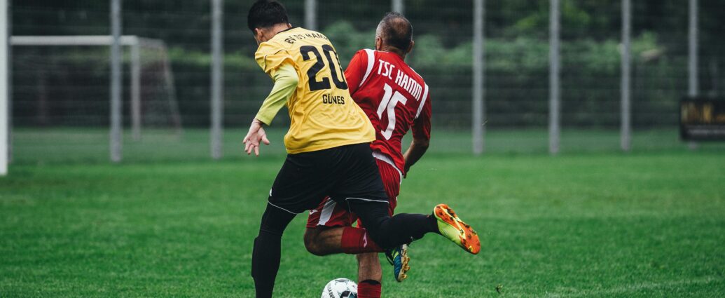 Two soccer players in action on a vibrant green field during a daytime match.